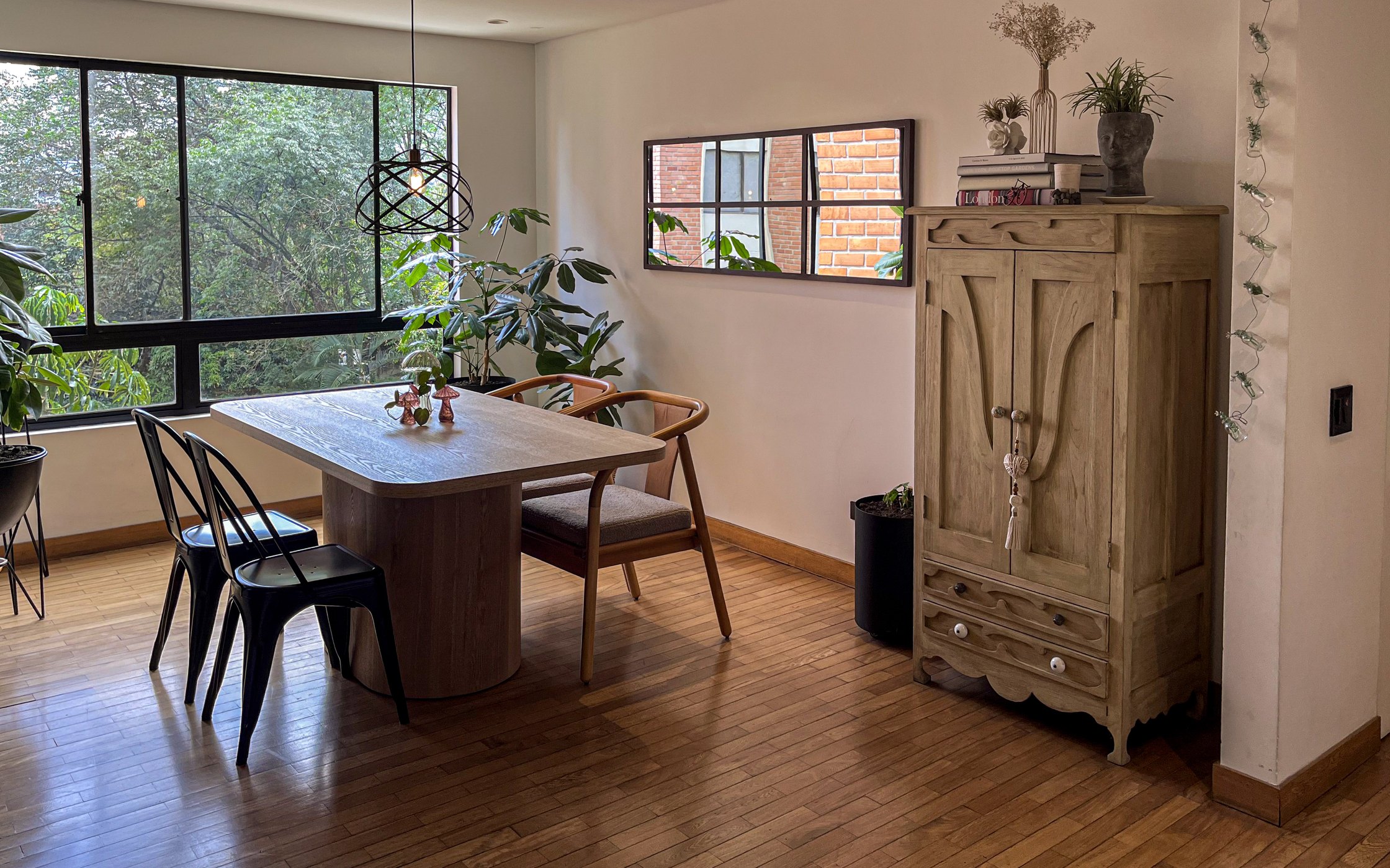 Comedor independiente con mesa en madera, ventanal a los árboles y piso en madera natural